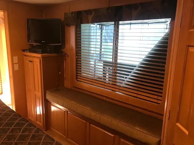 Slide: The Image of Interior of a 2007 Thoroughbred houseboat with TV, window seat, and wooden cabinetry. - 27