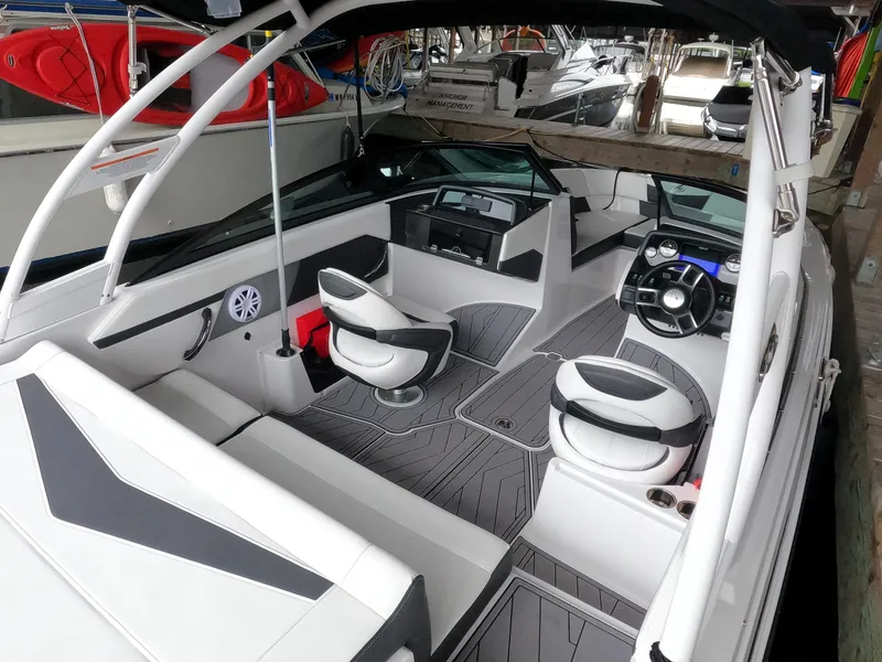 Slide: The Image of 2023 Monterey M-22 boat interior with modern seating and dashboard, docked at marina. - 11
