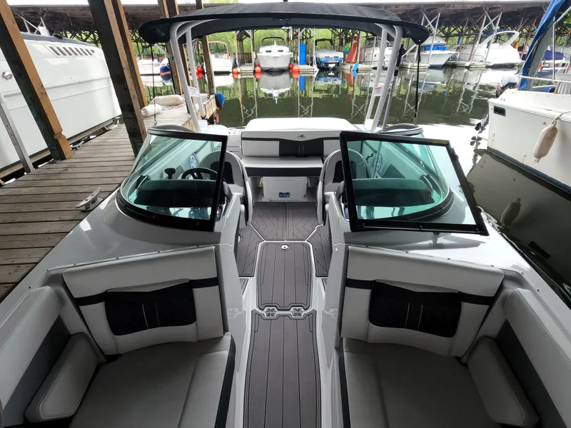 Slide: The Image of 2023 Monterey M-22 boat interior with seating and open windshield, docked at marina. - 47