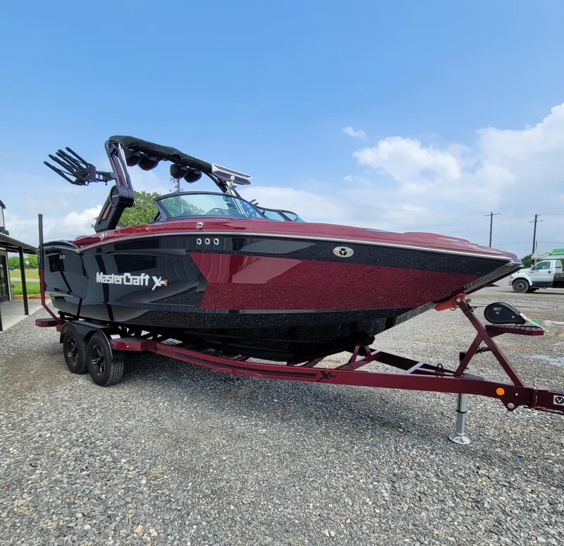 Slide: The Image of 2023 MasterCraft XStar S boat on trailer, parked outdoors under blue sky. - 14