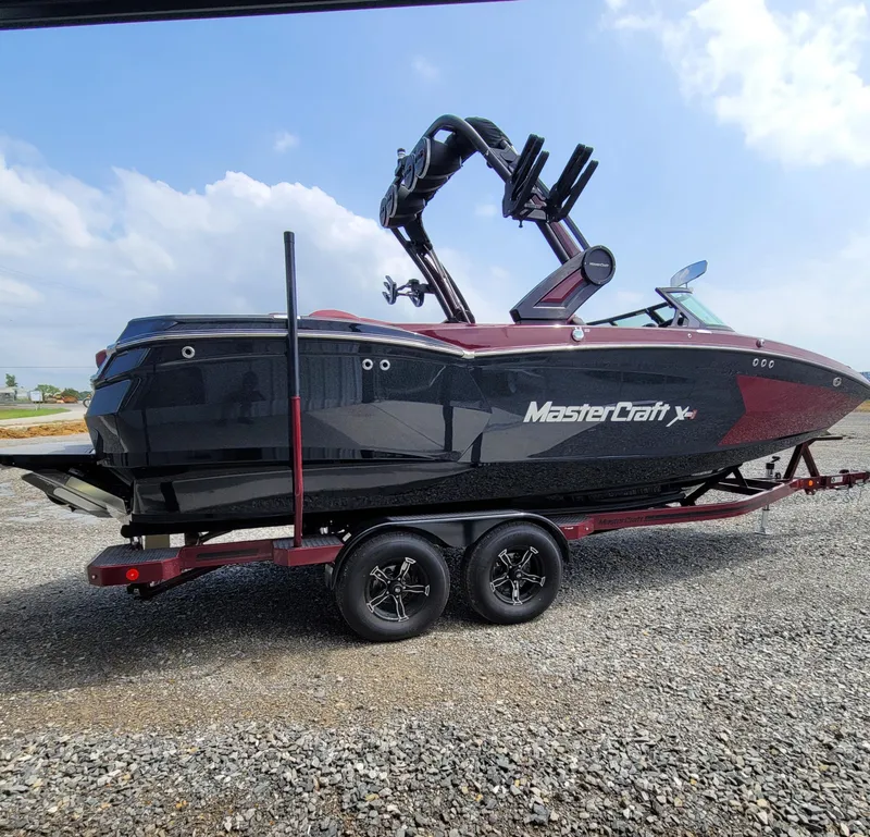 Slide: The Image of 2023 MasterCraft XStar S boat on trailer, black and red design, parked outdoors. - 19