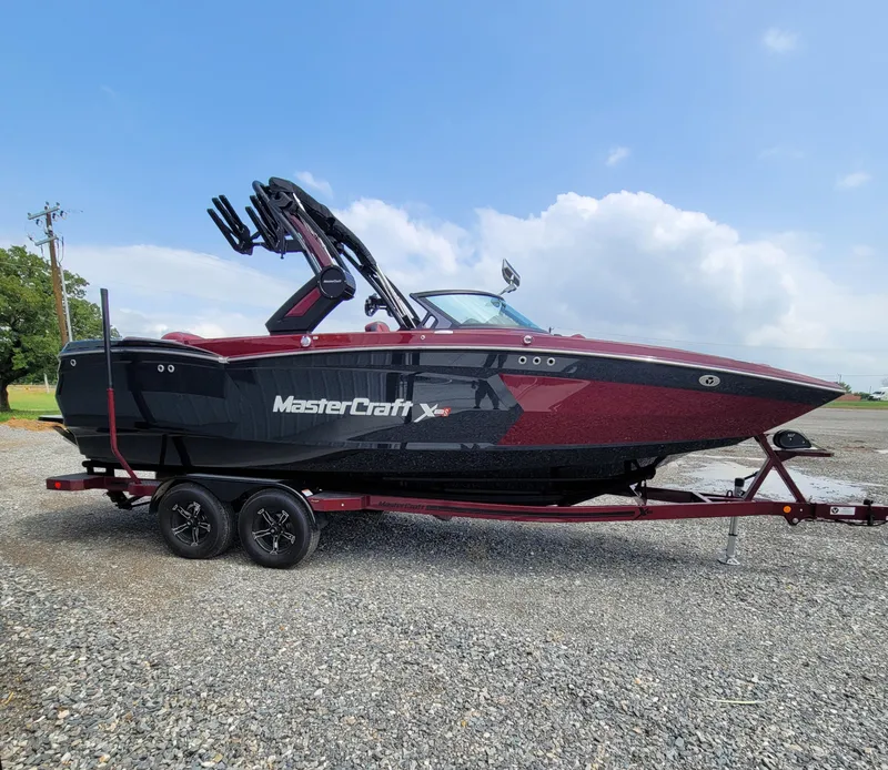 Slide: The Image of 2023 MasterCraft XStar S boat on trailer, parked outdoors. - 2