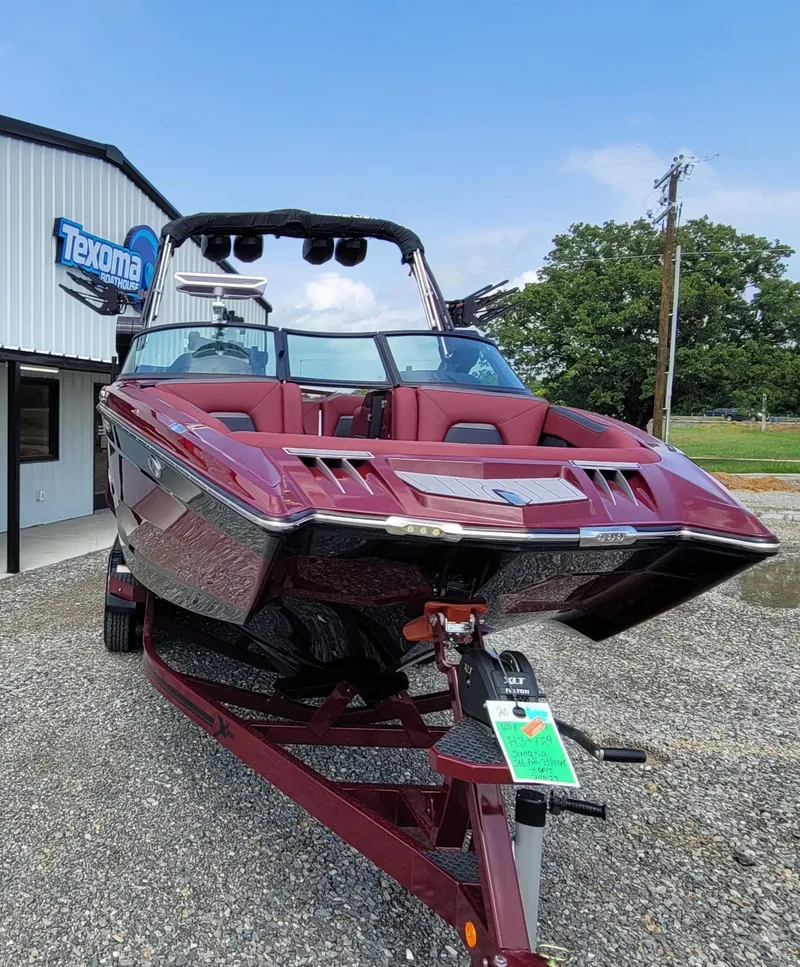 Slide: The Image of 2023 MasterCraft XStar S boat in maroon, parked on a trailer outside a building. - 4