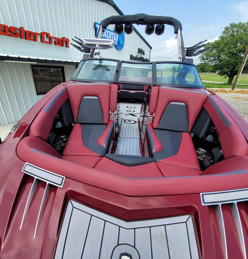 Slide: The Image of 2023 MasterCraft XStar S boat with red interior, parked outside dealership. - 7
