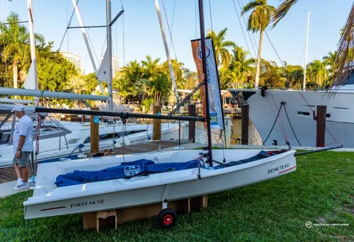 Slide: The Image of 2024 Beneteau First 14 SE sailboat displayed on grass near marina. - 2