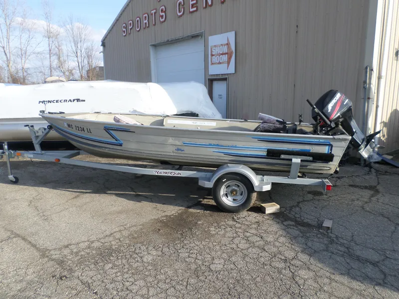 Slide: The Image of 1983 Sea Nymph 16 boat on trailer outside sports center. - 1