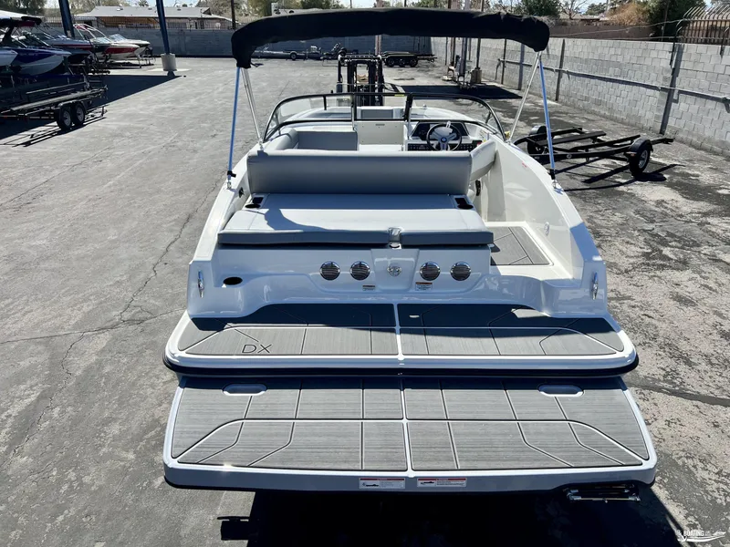 Slide: The Image of 2023 Bayliner DX2050 boat with spacious deck and seating, parked in a marina. - 1
