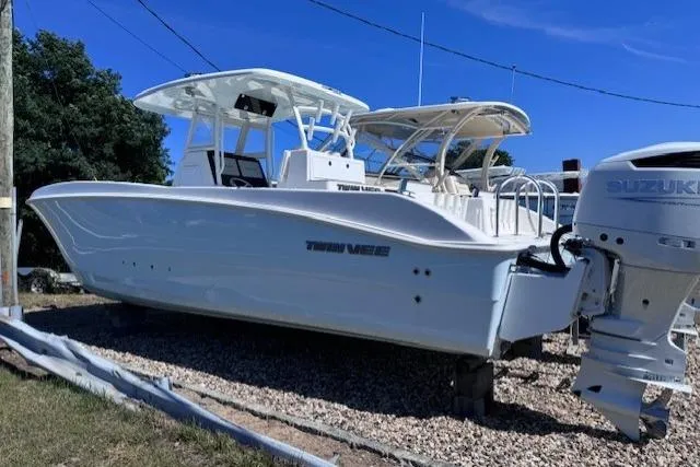 The Image of 2023 Twin Vee 280 GFX CC boat with Suzuki outboard motor, parked on gravel. - 0