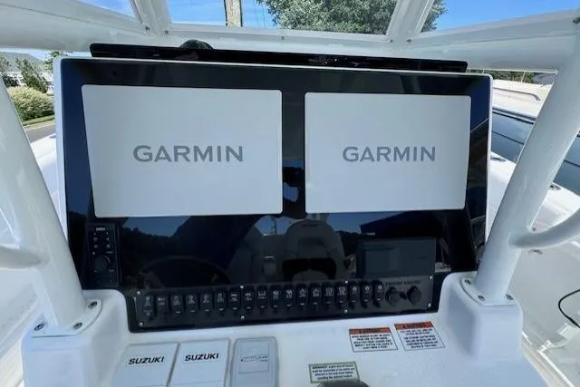 Slide: The Image of 2023 Twin Vee 280 GFX CC boat dashboard with dual Garmin displays and Suzuki controls. - 14