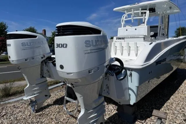 Slide: The Image of 2023 Twin Vee 280 GFX CC boat with dual Suzuki 300 engines, parked on gravel. - 2