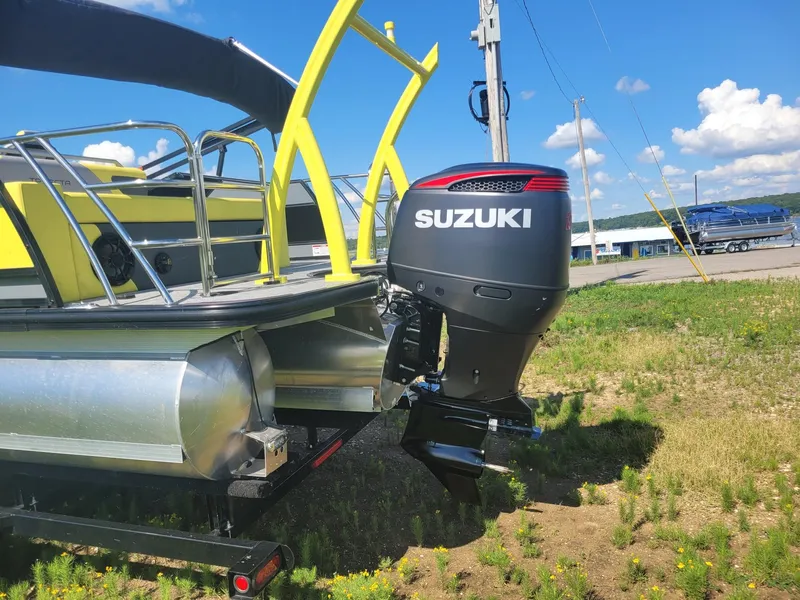 Slide: The Image of A 2023 Trifecta 23 UL SS pontoon boat with Suzuki outboard motor on a sunny day. - 2