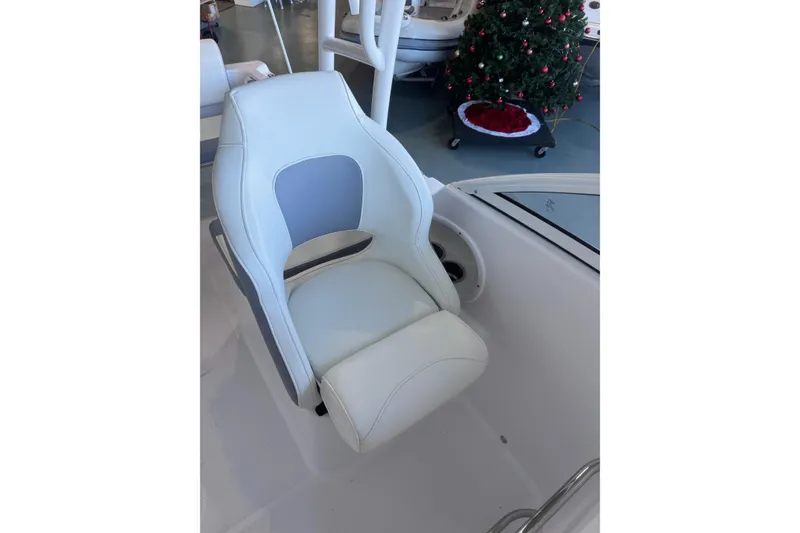 Slide: The Image of 2023 Release 230 DC boat seat with white and gray upholstery, Christmas tree in background. - 5