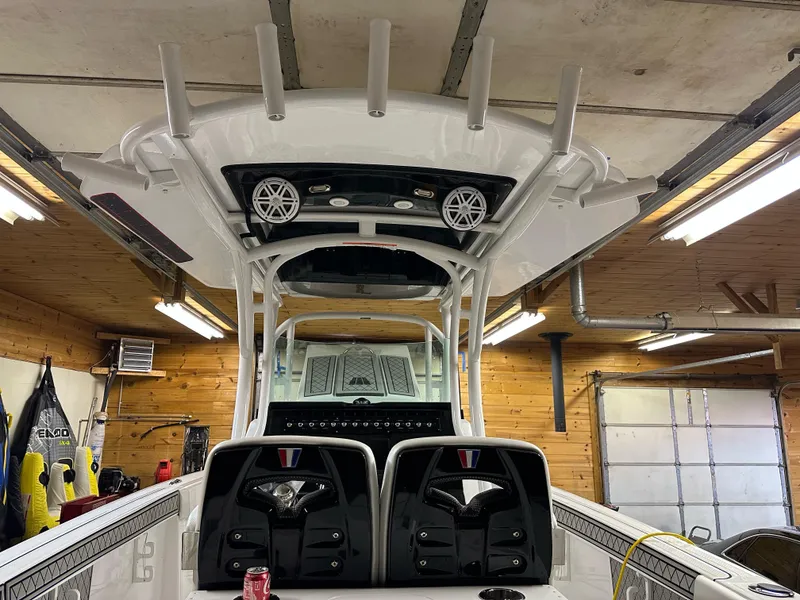 Slide: The Image of 2021 Wellcraft 262 Fisherman boat interior in a garage, featuring rod holders and speakers. - 23