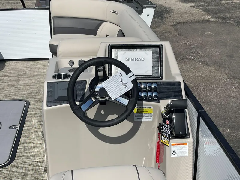 Slide: The Image of 2024 Harris Sunliner 250 boat dashboard with Simrad display and steering wheel. - 4