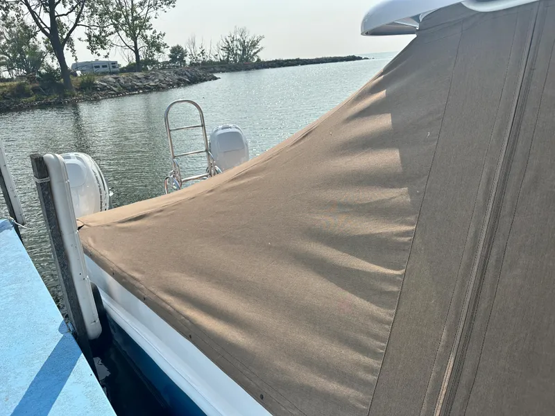 Slide: The Image of 2023 Twin Vee 340 GFX boat with a tan cover docked by a lake. - 14