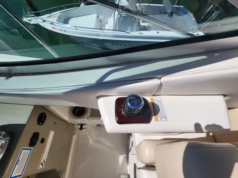 Slide: The Image of 2012 Sea Ray 350 Sundancer interior with control panel and seating, overlooking docked boat. - 19