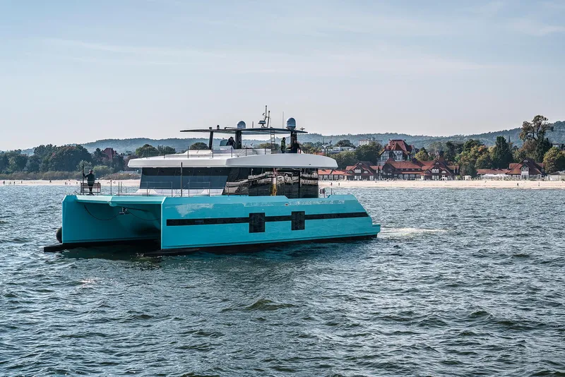 Slide: The Image of 2018 Sunreef 68 Supreme catamaran sailing near a scenic coastal town. - 5