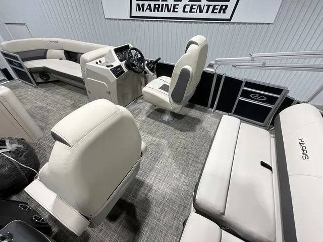 Slide: The Image of 2023 Harris Cruiser 230 interior with beige seating and modern dashboard at a marine center. - 10