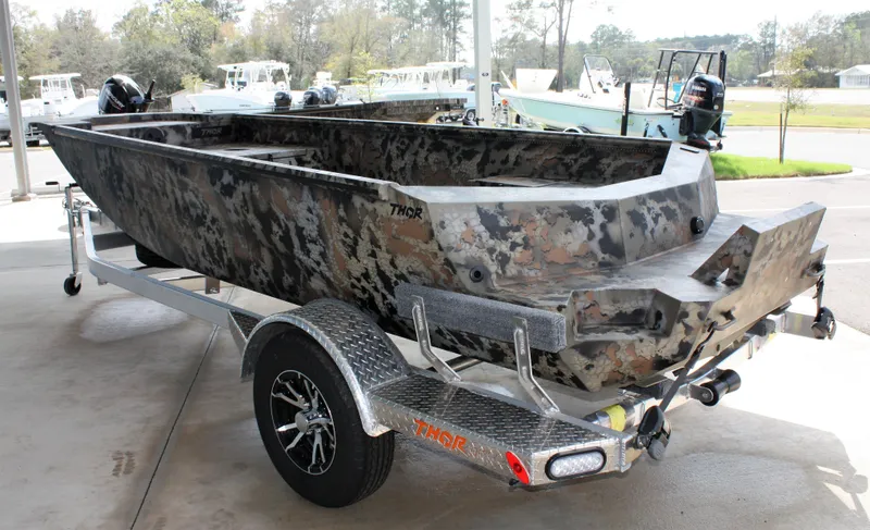 Slide: The Image of 2023 Thor Lake Hammer boat on a trailer, camo design, parked outdoors. - 10