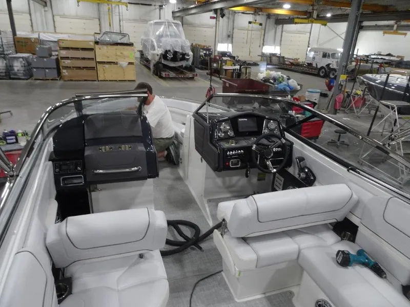 Slide: The Image of 2023 Formula 240 Bowrider interior with white seating and cup holders in a workshop. - 9