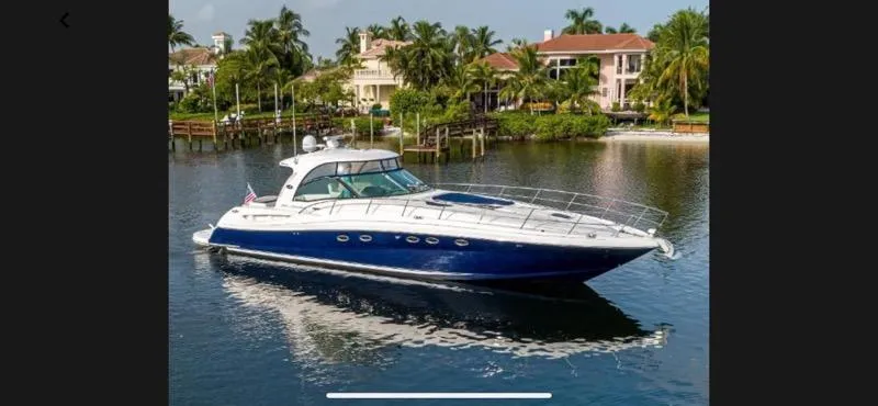 Slide: The Image of 2005 Sea Ray 500 Sundancer yacht cruising on a serene waterway near luxury homes. - 1
