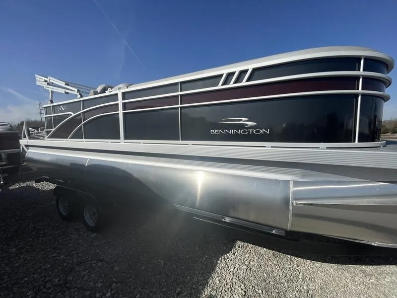 Slide: The Image of 2023 Bennington 22 SXL pontoon boat on a trailer under a clear blue sky. - 1