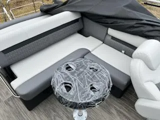 Slide: The Image of 2024 Sweetwater 2286SFL boat interior with gray and white seating and a covered table. - 17