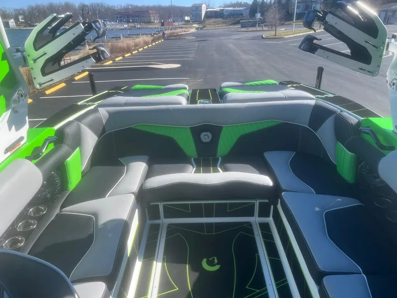 Slide: The Image of 2023 Centurion Fi23 boat interior with green and gray seating, docked in a marina. - 10