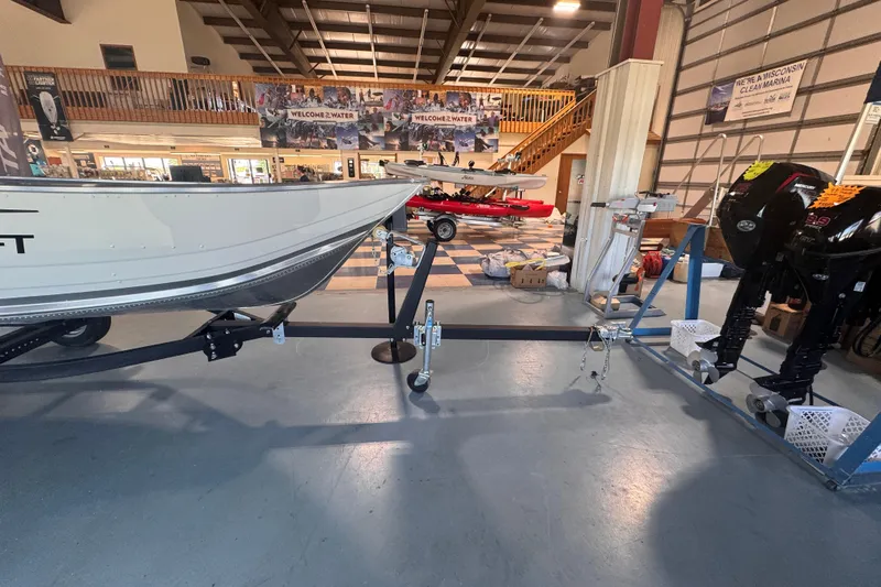 Slide: The Image of 2023 Starcraft Alaskan 12 boat displayed indoors with outboard motors. - 2