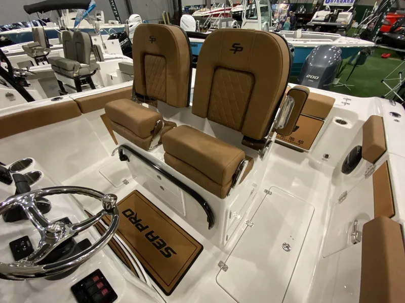 Slide: The Image of 2023 Sea Pro 259 DLX boat interior with tan seats and steering wheel. - 8