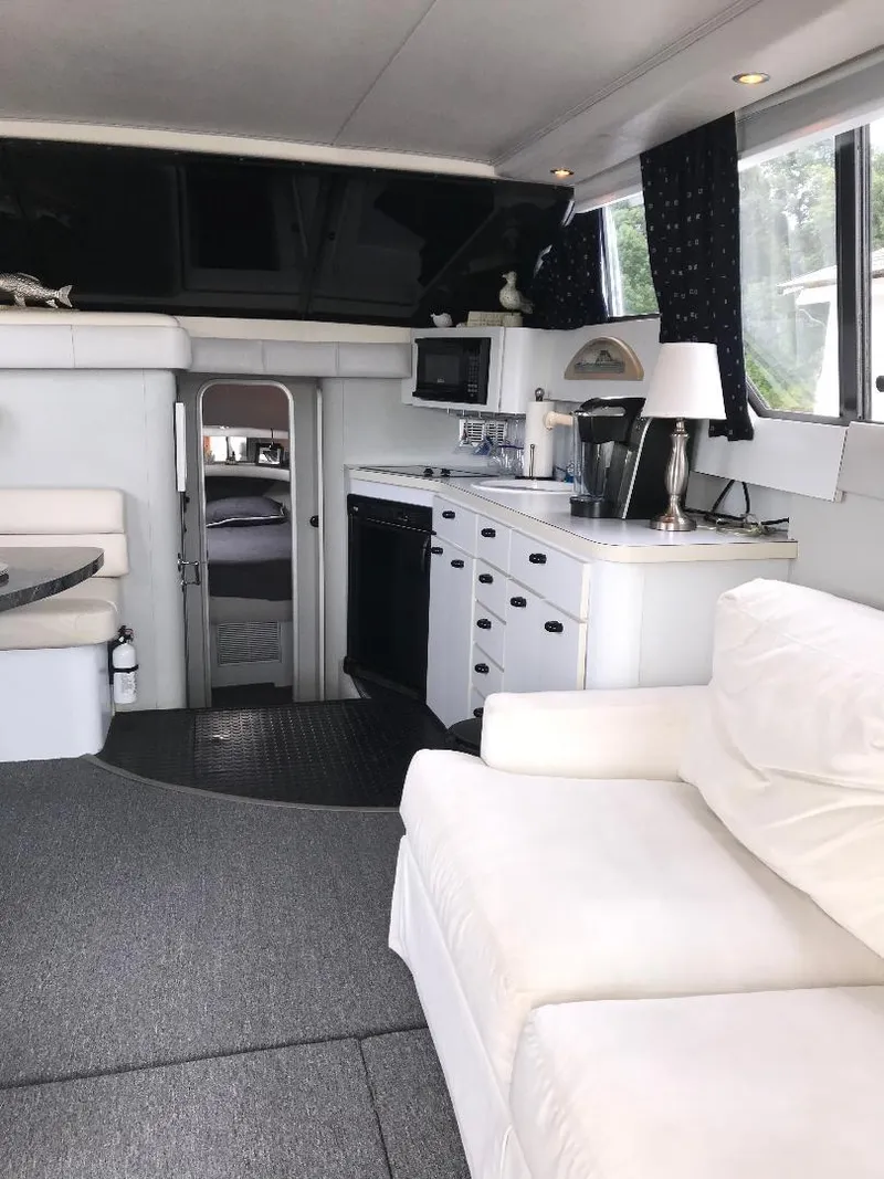 Slide: The Image of 1990 Mainship Mediterranean yacht interior with white sofa, kitchenette, and modern amenities. - 26