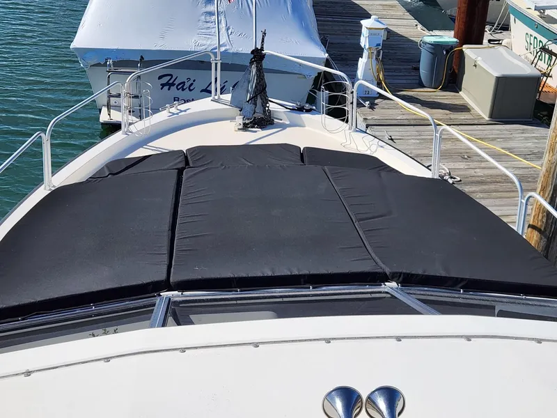 Slide: The Image of 1990 Mainship Mediterranean boat docked, featuring a black sunpad on the bow. - 3