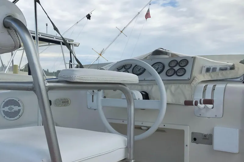 Slide: The Image of 1990 Mainship Mediterranean boat helm with steering wheel and gauges, under a cloudy sky. - 30