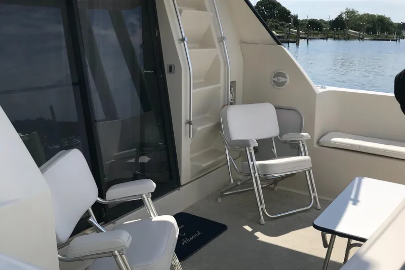 Slide: The Image of 1990 Mainship Mediterranean yacht deck with chairs, table, and waterfront view. - 31