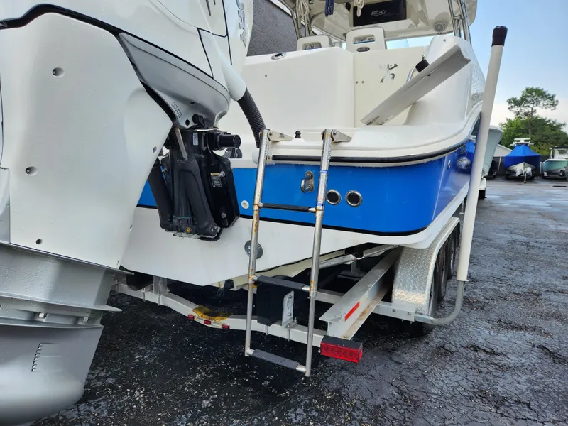 Slide: The Image of 2008 Boston Whaler 320 Outrage Cuddy Cabin boat with ladder and motor, parked on trailer. - 2