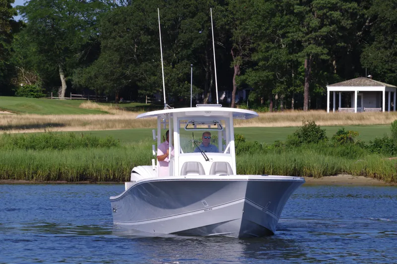 Slide: The Image of 2024 Regulator 30XO boat cruising on a calm lake near a grassy shoreline. - 0