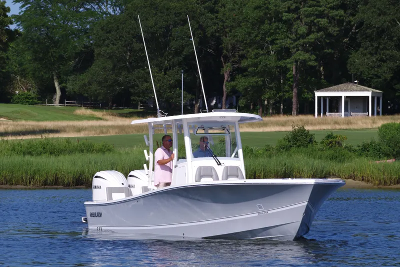 Slide: The Image of 2024 Regulator 30XO boat on a calm lake with two people onboard. - 12