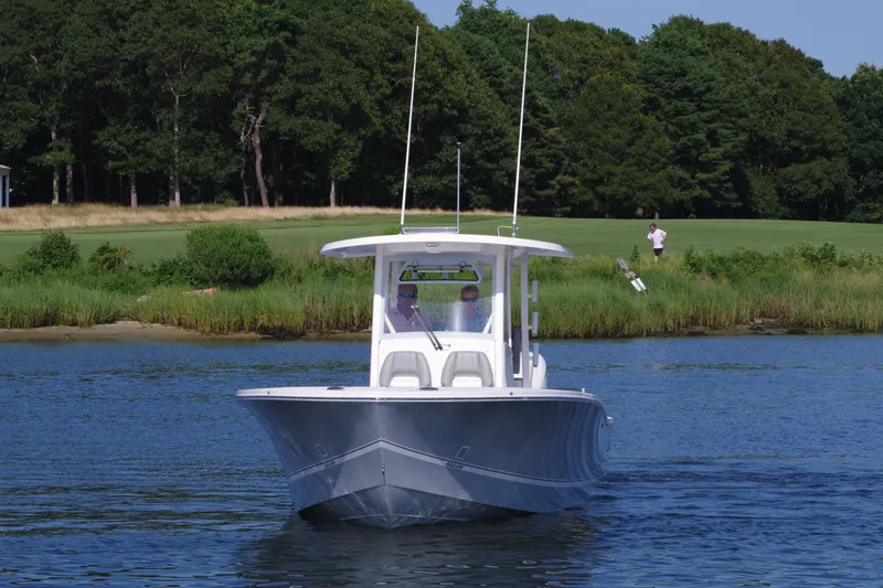 Slide: The Image of 2024 Regulator 30XO boat cruising on a calm lake near a forested shoreline. - 2