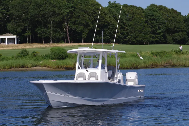 Slide: The Image of 2024 Regulator 30XO boat cruising on a calm lake with a forested background. - 3