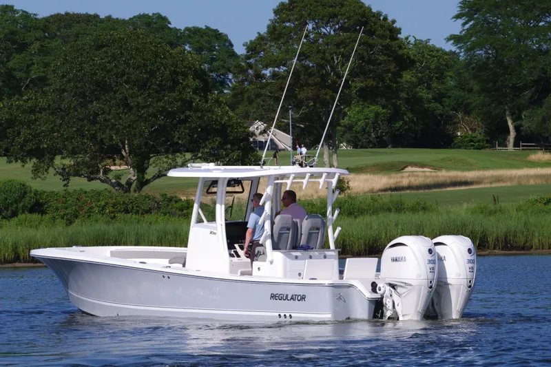 Slide: The Image of 2024 Regulator 30XO boat on a serene lake with lush greenery. - 5