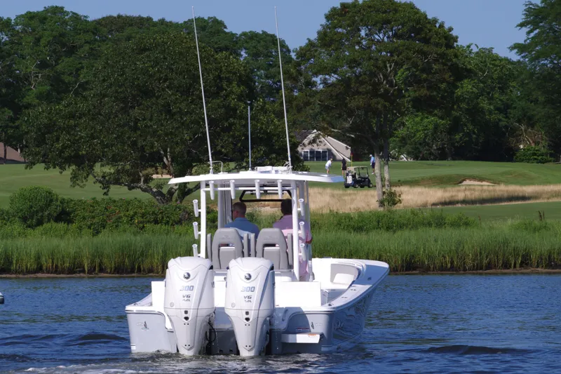 Slide: The Image of 2024 Regulator 30XO boat cruising on a lake with lush greenery in the background. - 8