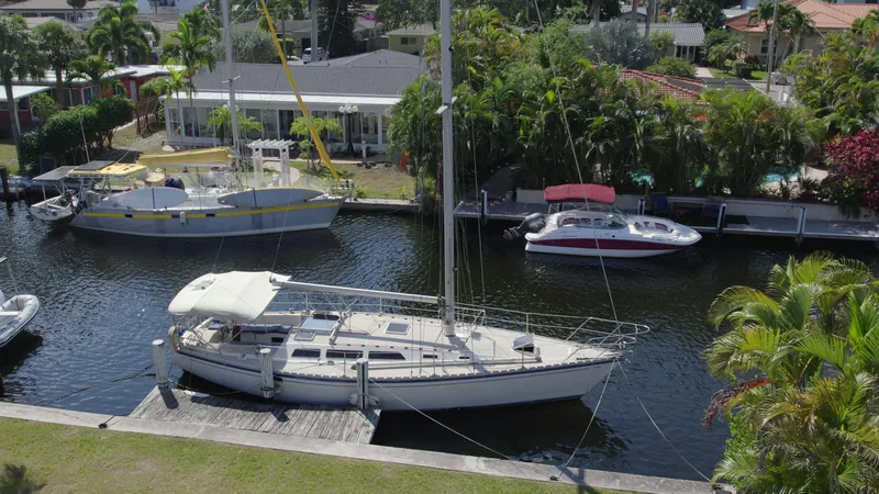 Slide: The Image of 1986 O'Day 39 sailboat docked in a scenic canal with lush greenery. - 2