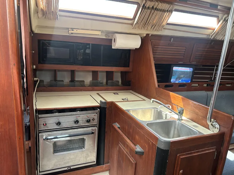Slide: The Image of 1986 O'Day 39 yacht kitchen with stove, sink, and wooden cabinetry. - 46