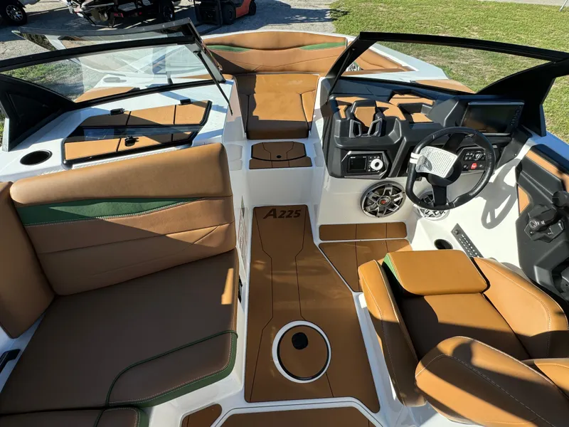 Slide: The Image of 2023 Axis A225 boat interior with tan and green upholstery, modern dashboard, and spacious seating. - 14