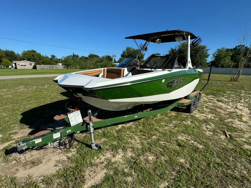 Slide: The Image of 2023 Axis A225 green and white boat on a trailer in a grassy area. - 2