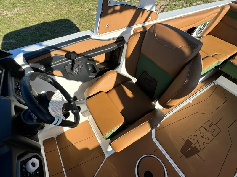 Slide: The Image of 2023 Axis A225 boat interior with brown and green seating, steering wheel, and dashboard. - 21