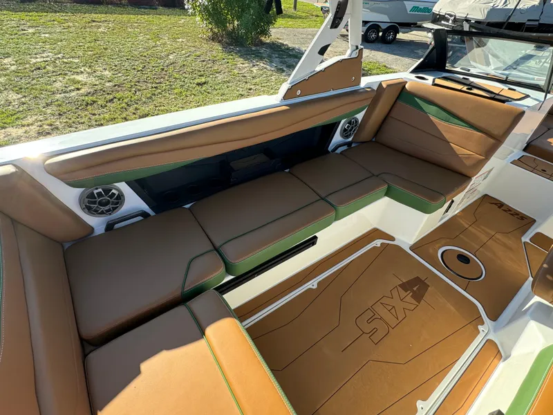 Slide: The Image of 2023 Axis A225 boat interior with brown and green seating, speakers, and deck. - 25