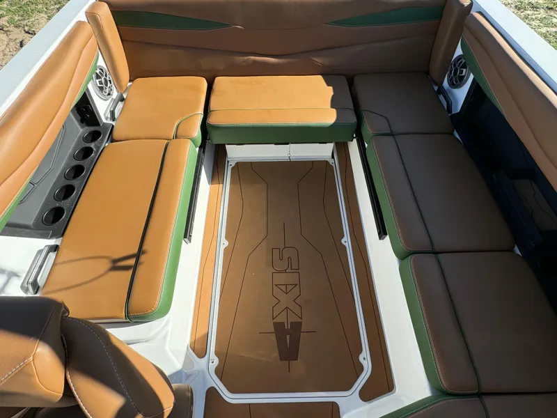 Slide: The Image of 2023 Axis A225 boat interior with brown and green seating, cup holders, and speakers. - 28
