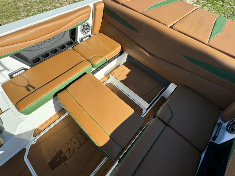 Slide: The Image of 2023 Axis A225 boat interior with tan and green upholstery, cup holders, and speakers. - 29