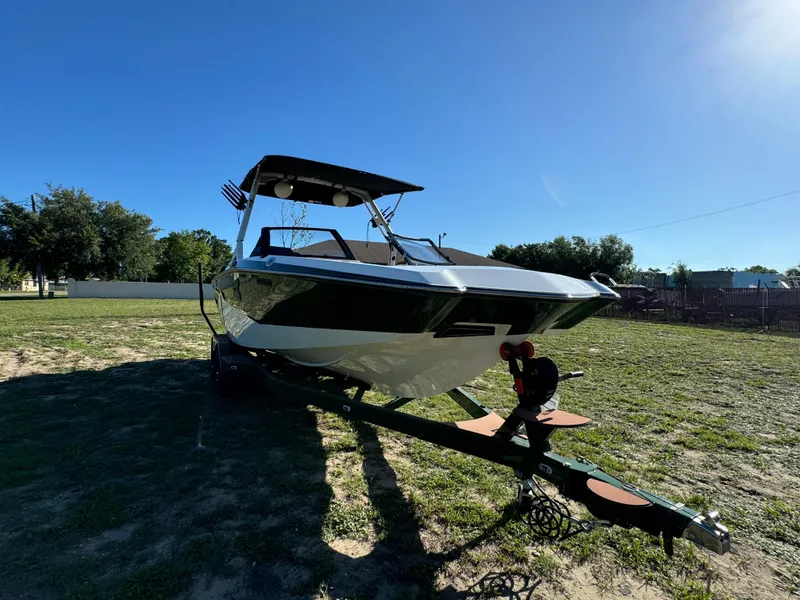 Slide: The Image of 2023 Axis A225 boat on a trailer in a grassy area under a clear blue sky. - 3